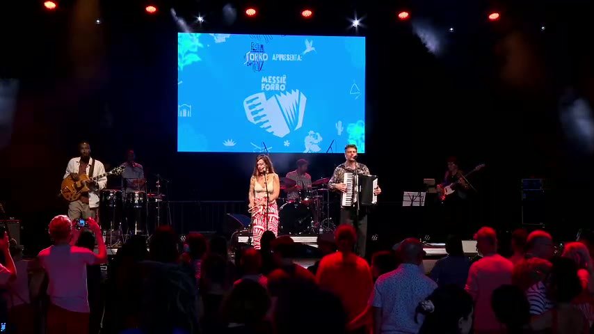 Forró Brasil en concert avec le public et le logo Messiê Forró sur scène
